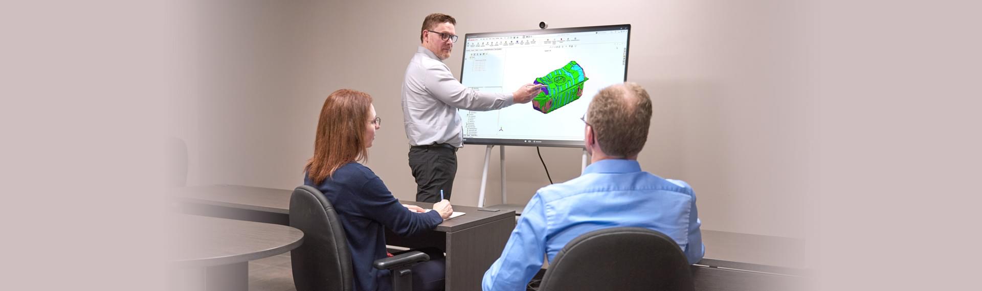 Three Spectra Premium engineers discussing the design of fuel delivery reservoirs on interactive computer